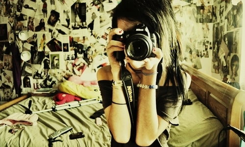 девушка в комнате с облеенными стенами в фотографиях с камерой в руках селфи в зеркало