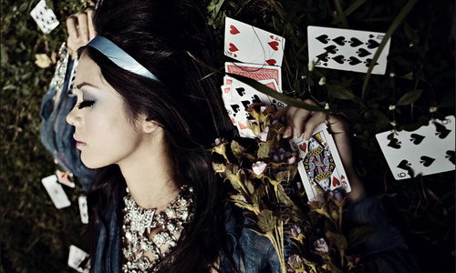 девушка с длинными ресницами лежит среди рассыпаной колоды карт