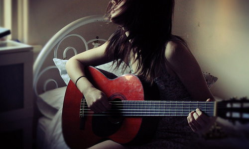 девушка с гитарой на кровати у окна