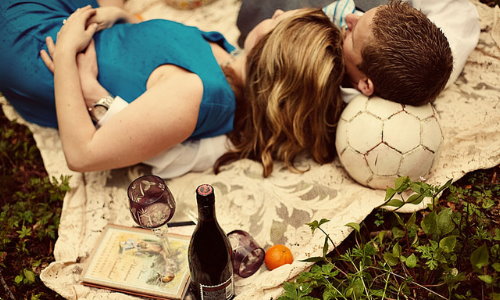 парень с девушкой лежат в обнимку на пикнике подперев голову футбольным мячем
