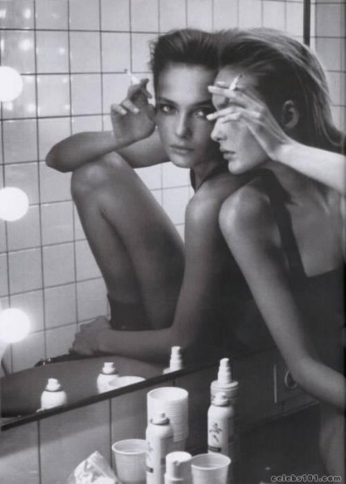 Девушка спиной к спине сама с собой у зеркала с сигаретой