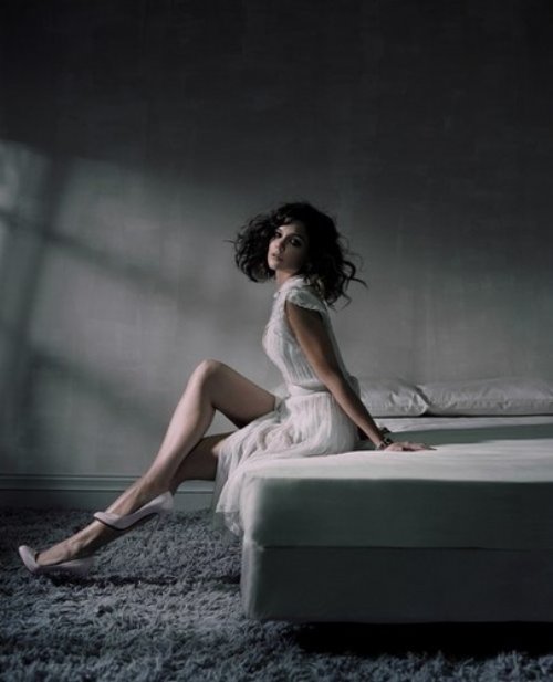 Девушка с растрепанными волосами в белом платье на краю кровати