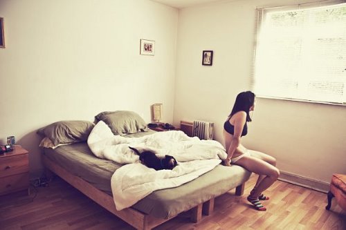 Девушка в нижнем белье сидит на краю кровати