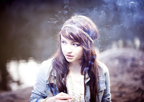 Девушка пускает дым и смотрит всторону