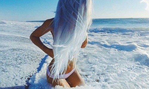 девушка с голубыми волосами в белом купальнике сидит в морской пене