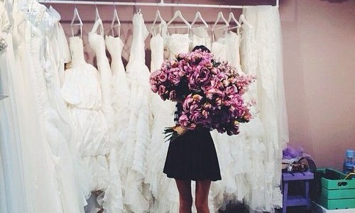 девушка с огромным букетом роз не видно лица в свадебном салоне выбирает себе платье