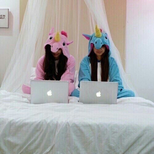 две подруги в пижамах единорогах с ноутбуками apple