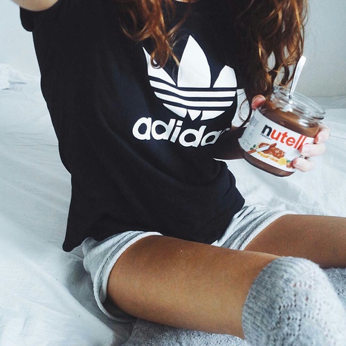 девушка в гетрах коротких шортах и футболке Adidas с Nutella