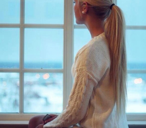 блондинка в белом свитере у окна со спины