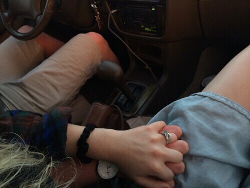 Влюбленные в летней одежде в машине держатся за руки