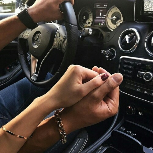 Влюбленные с браслетами в машине держатся за руки