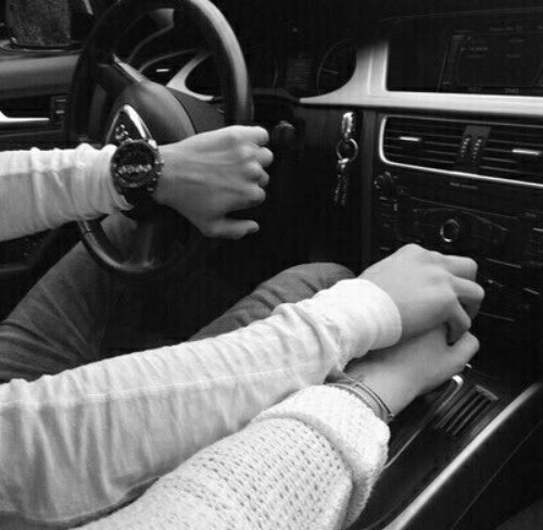 Влюбленные в свитерах в машине держатся за руки