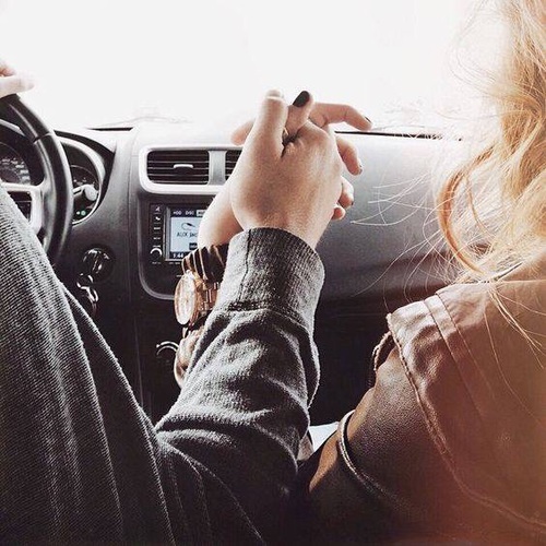 Влюбленные сзади со спины в машине держатся за руки