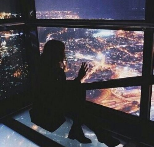 силуэт девушки глядящей вдаль на ночной город с высокого этажа не видно лица