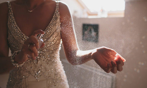 девушка в свадебном платье душится парфюмом
