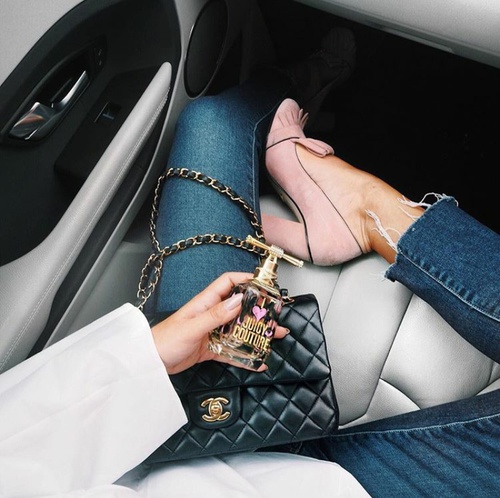 девушка в джинсах на сиденье автомобиля с флаконом парфюма