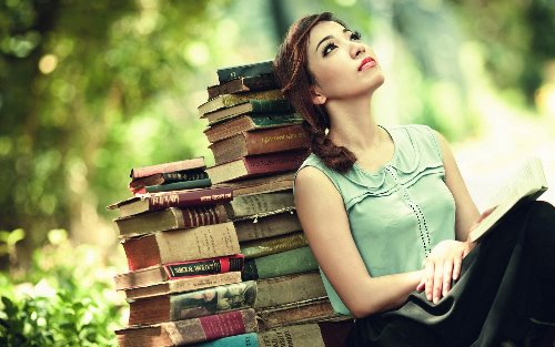 мечтательная девушка в лесу склонилась на стопку книг