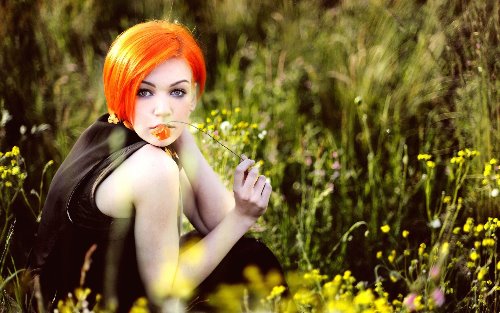 рыжая девушка прячется в траве с недлинными волосами