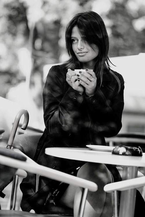 девушка в кафе с кружкой чая в руках в плаще с короткими волосами