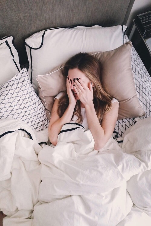 девушка в кровати закрыла лицо руками с черными ногтями