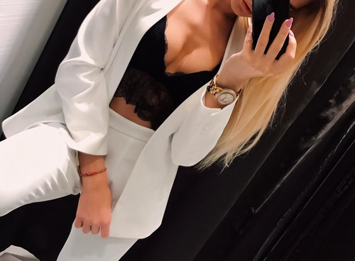 блондинка в белых брюках и пиджаке в зеркале