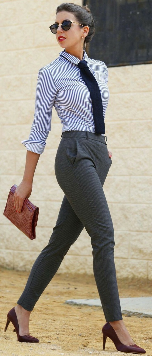 девушка в полосатой рубашке и брюках на улице с клатчем