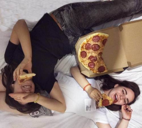 девушки веселятся поедая пиццу в гостях