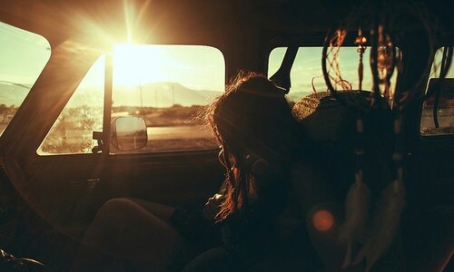 девушка без лица в автомобиле в лучах солнца с ловцом снов