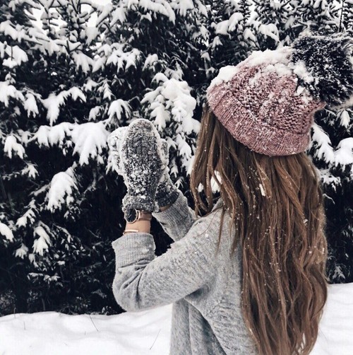 девушка без лица играет в снежки в свитере среди елок