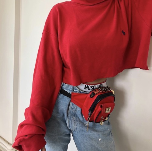 стильная девушка в джинсах и красной кофте с поясной сумкой