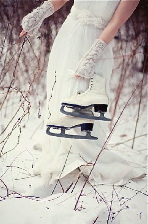 девушка в белом платье с коньками в руках в зимнем лесу