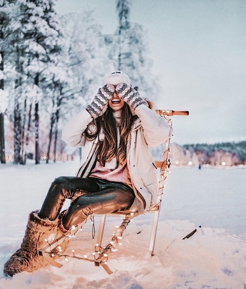 счастливая девушка с длинными волосами закрывает лицо руками в рукавицах зимой