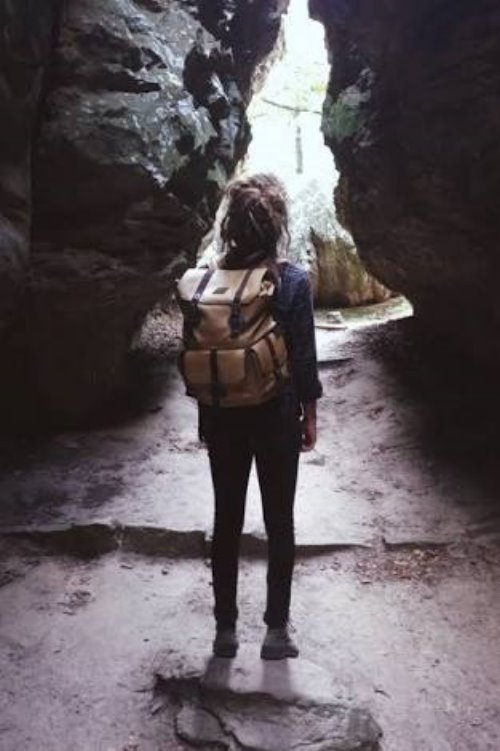 девушка со спины без лица с рюкзаком в каменной пещере