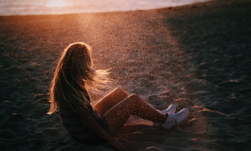 блондинка на песке в лучах солнца не видно лица