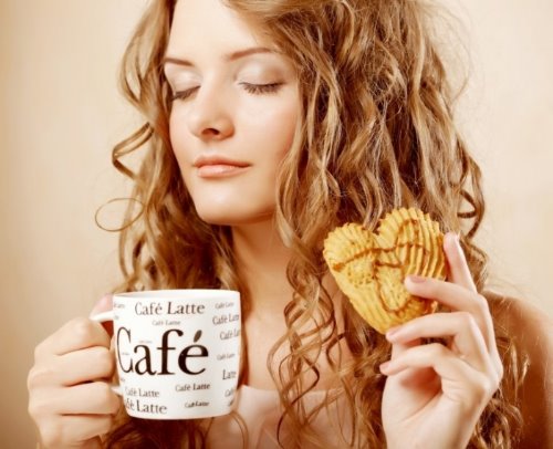 девушка пьет утренний кофе с печенькой