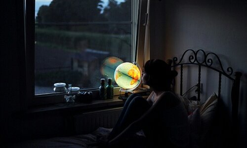 девушка на кровати в темной комнате на подоконнике светится глобус