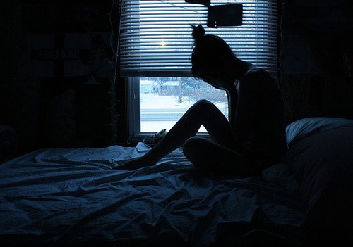 девушка плачет на кровати в темноте в комнате