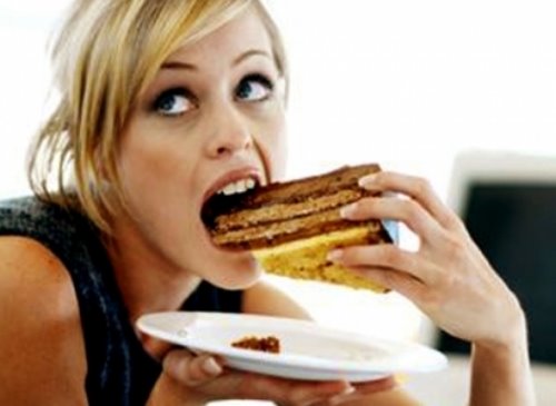 блондинка быстро ест торт смотря на часы
