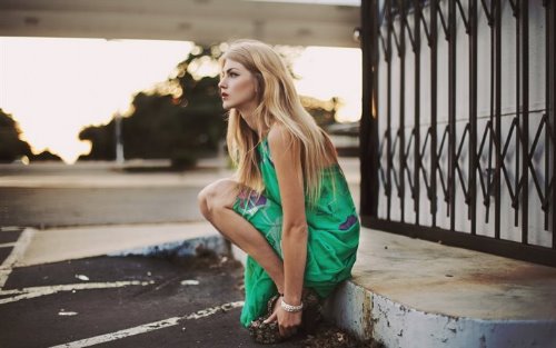 блондинка в длинном сарафане сидит на корточках в ожидании