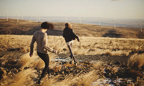 две девушки со спины бегут к ветряным мельницам