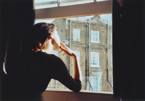 девушка без лица с сигаретой смотрит в открытое окно