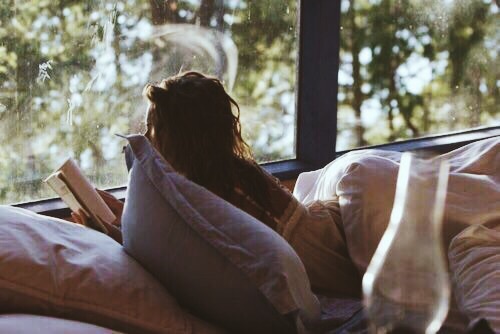 девушка с книгой без лица у окна под одеялом