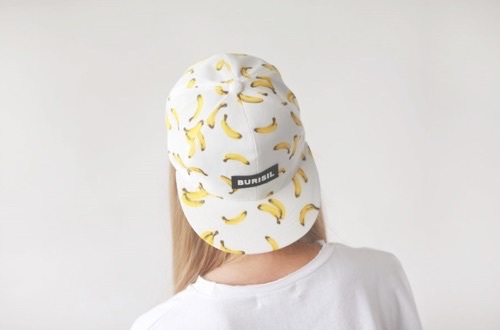  білявка в білій футболці зі спини в кепці з бананами