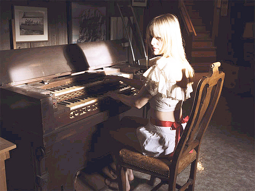 девушка играет на пианино дома в темной комнате
