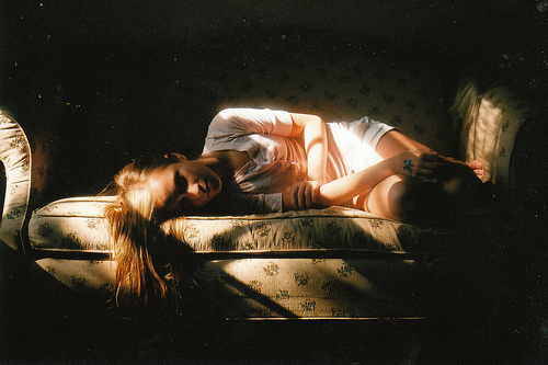дівчина лежить на канапі в кімнаті в променях ранкового сонця