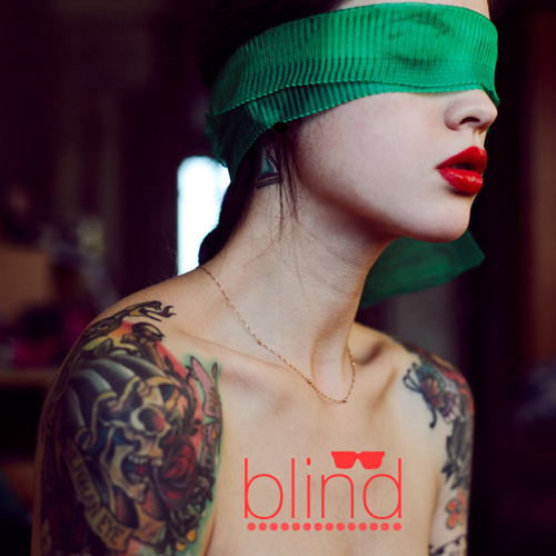 девушка с татуировками на руках с ярко красной помадой завязала глаза зеленой лентой