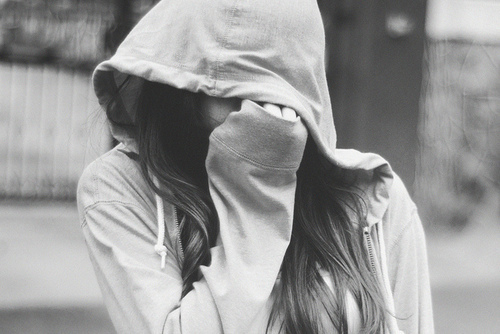 девушка прячется под капюшоном толстовки прикрывая лицо