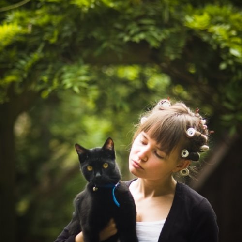русая девушка в бигуди прогуливается с черной кошкой