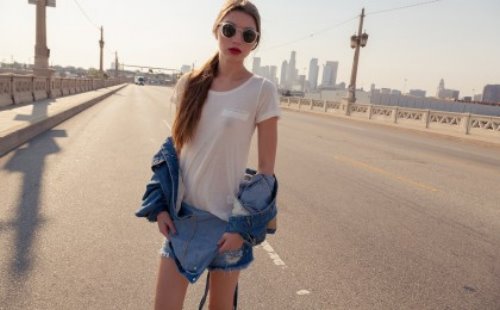 русая девушка в круглых солнечных очках в джинсовом комбинезоне на дороге