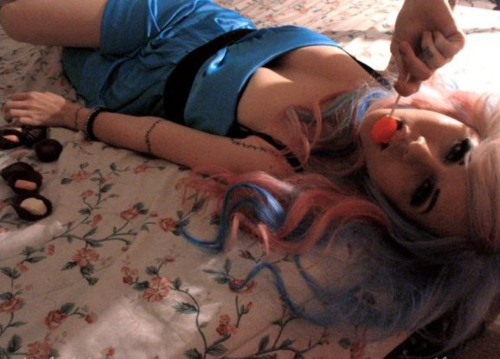 девушка в синем платье поедает конфеты лежа на кровати
